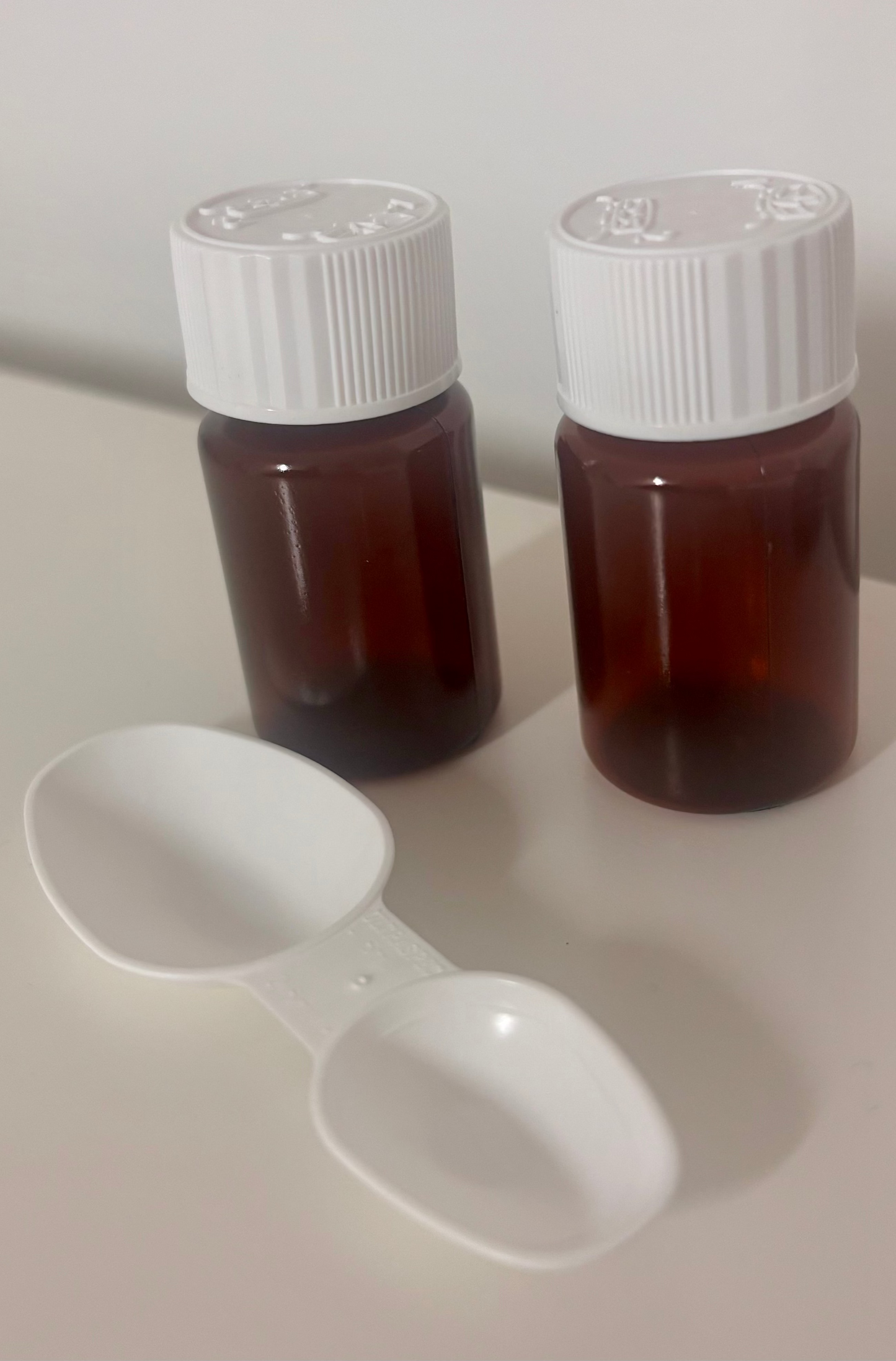 Set of two small child-proof amber medicine bottles with medicine spoon